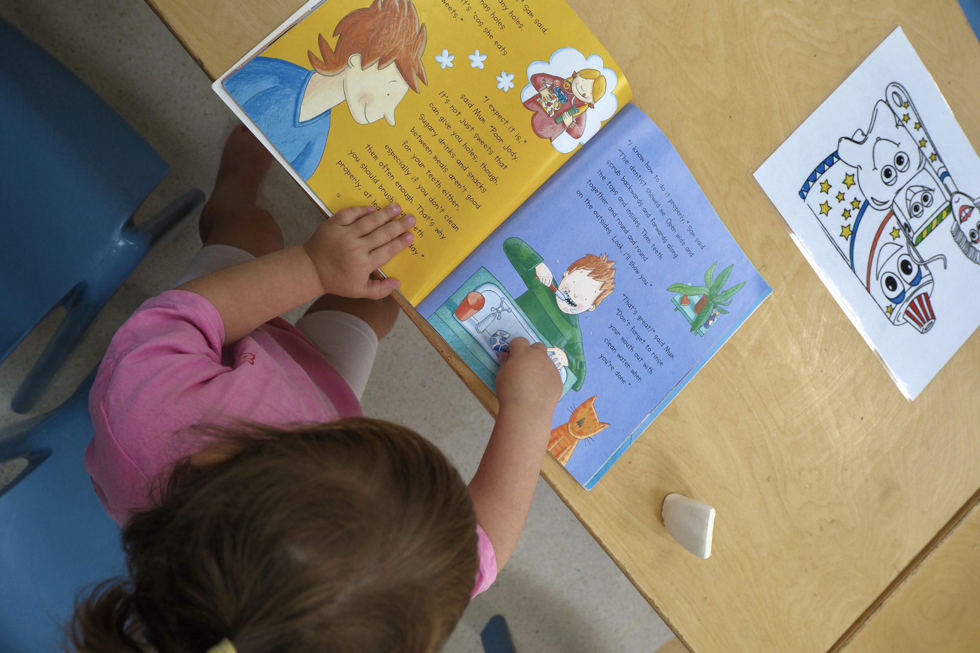 A young child turning the pages of a picture book at a table